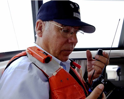 VHF radios are standard equipment aboard all marine vessels. Here, USCG Auxiliarist Bob Sterzenbach uses a VHF marine radio to contact Radio Newport during a safety patrol off Southern California. Photo credit: USCG Auxiliary.